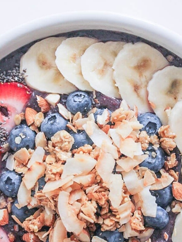 Tropical Acai Bowl topped with banana slices, strawberry slices, chia seeds, blueberries, granola, and nuts.