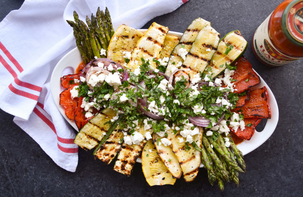 Overhead view of a platter of grilled vegetables on top of a red and white dish cloth.